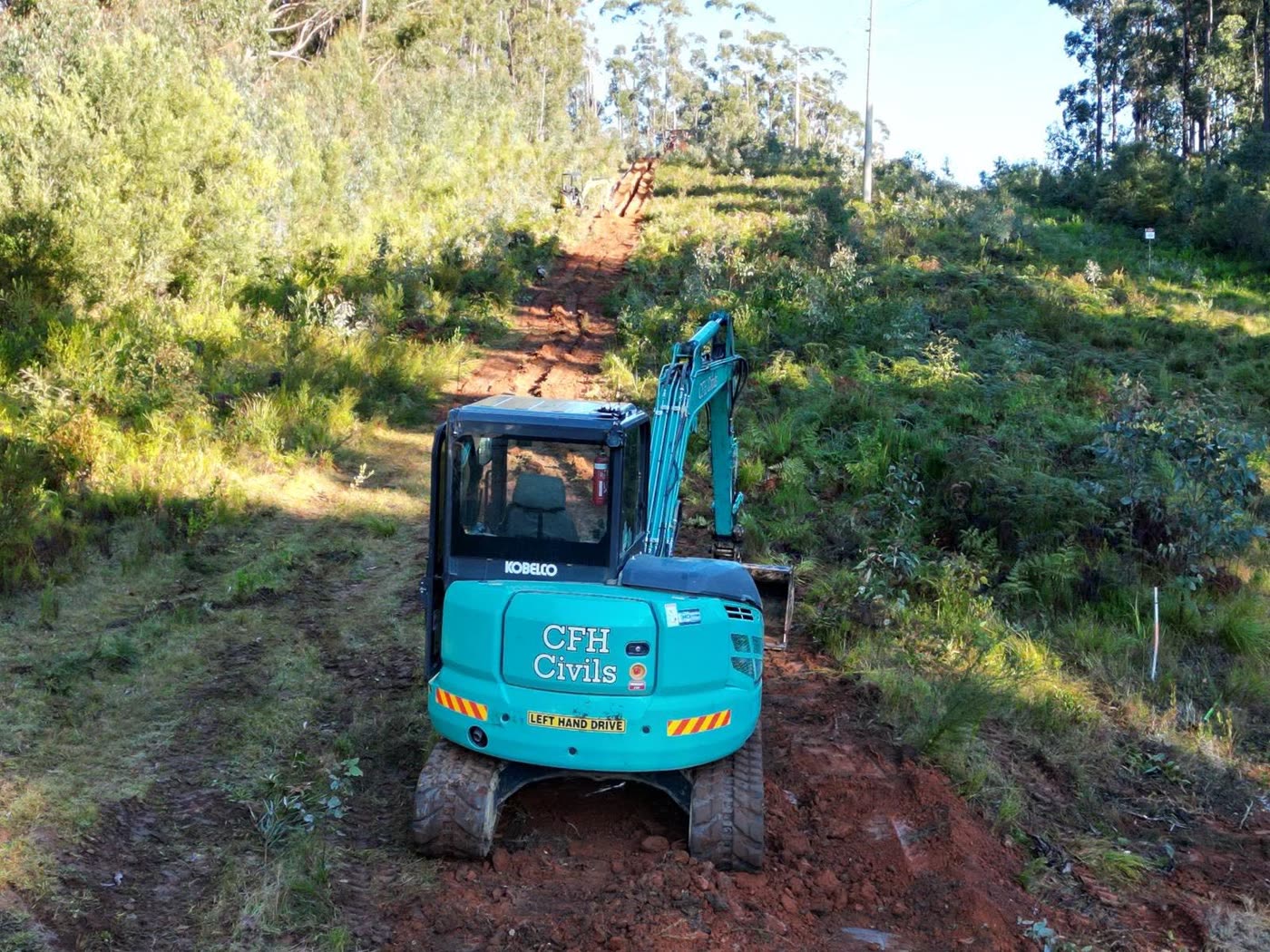 CFH Civils branded Kobelco excavator working a bush access track on a utility corridor